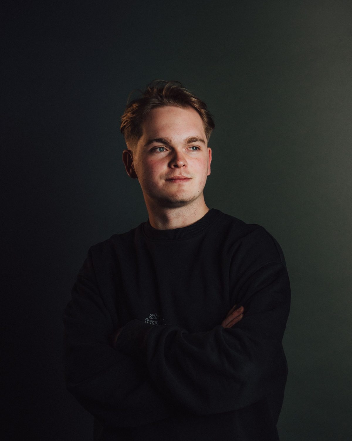 Mike Tunes in a black sweater, arms crossed